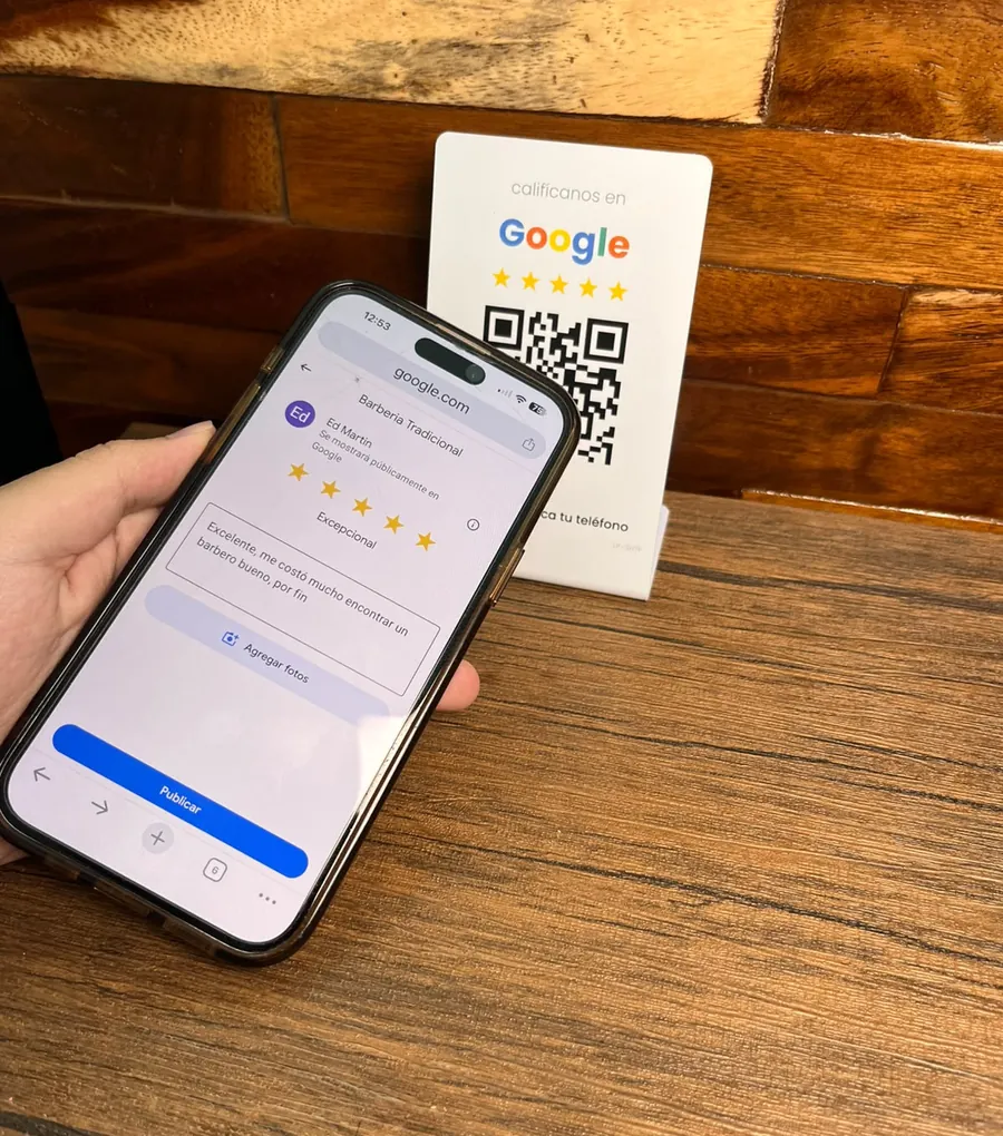 Un cliente sostiene su teléfono con la reseña de Google ya escrita y lista para publicar, junto al display de mostrador de LinkPro.